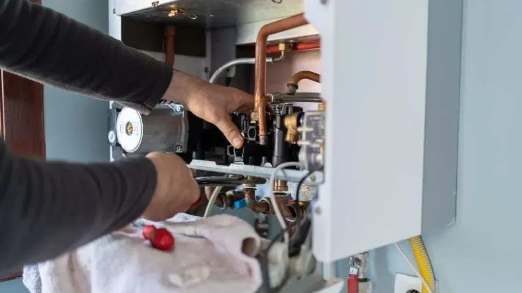 Kombi bakımı sırasında iç aksamda çalışan teknisyen