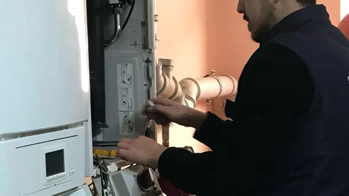 Teknisyenin kazan dairesinde kombi gaz hattı ve baca bağlantısını kontrol etmesi